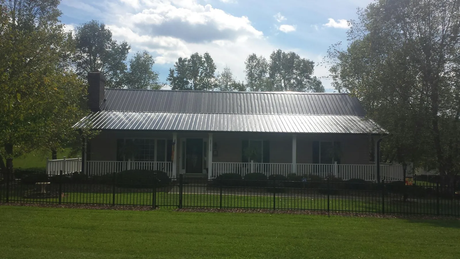 Gray metal roof on a brick ranch with a full width front porch — Gutter Guard Installation work by our crew in Washington